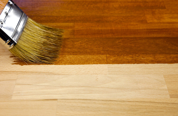 A brush painting a wooden floor