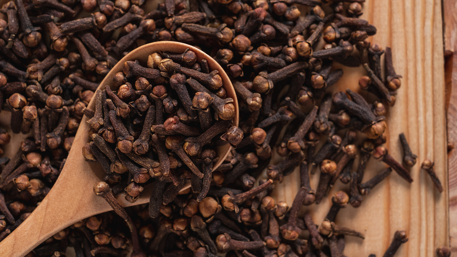 Cloves scattered on a wooden table.