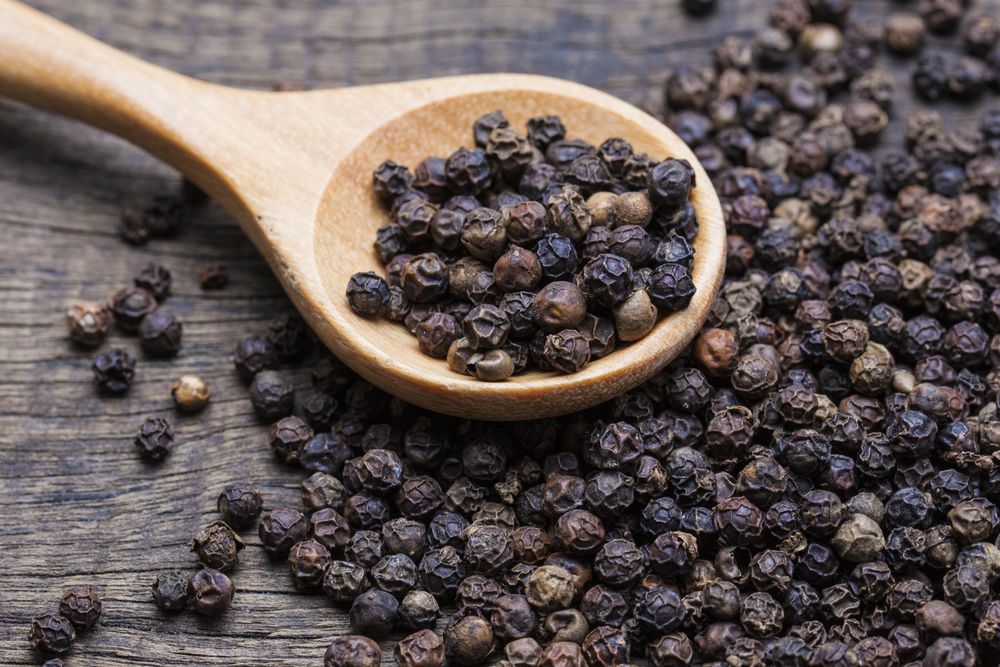Aromatic black pepper on a wooden spoon