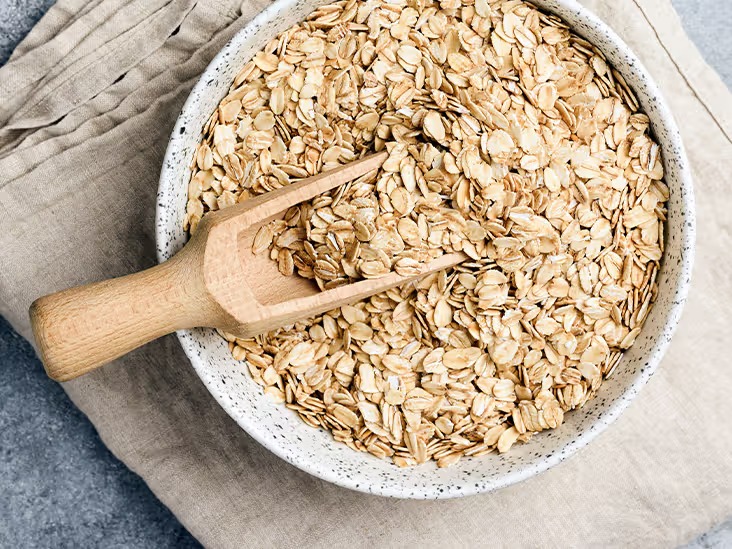 Oats in a bowl with a wooden spoon.