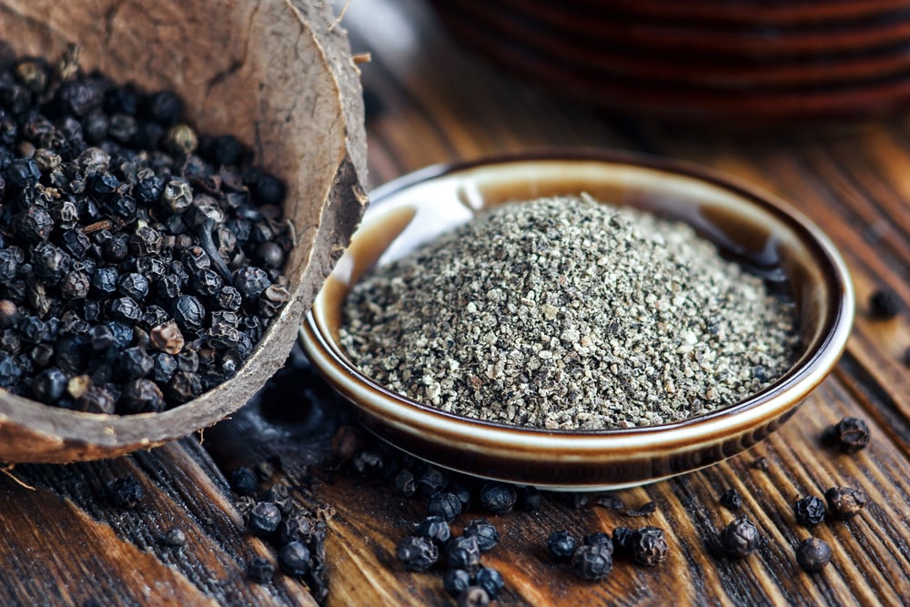 Black pepper powder and a coconut in a bowl