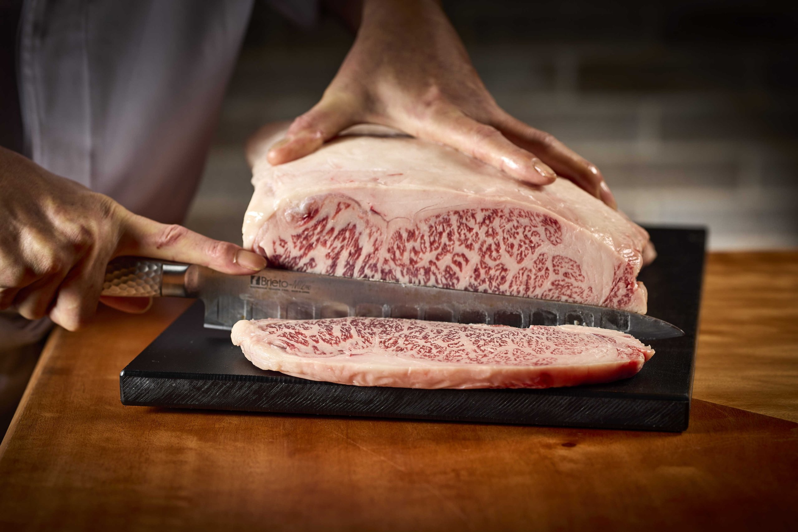 A person slicing Wagyu Beef on a cutting board