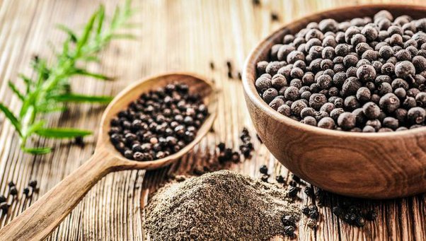 Black pepper powder in a wooden bowl and a spoon